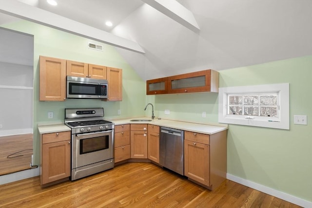 kitchen featuring visible vents, light countertops, light wood-style floors, stainless steel appliances, and a sink