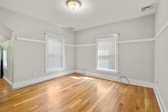 unfurnished room featuring visible vents, baseboards, and wood finished floors