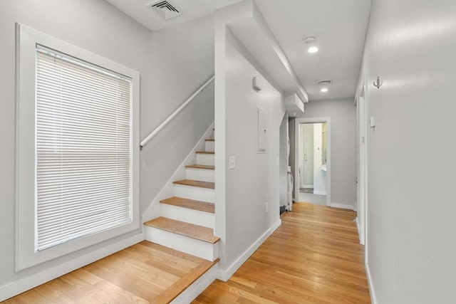 staircase with visible vents, baseboards, and wood finished floors