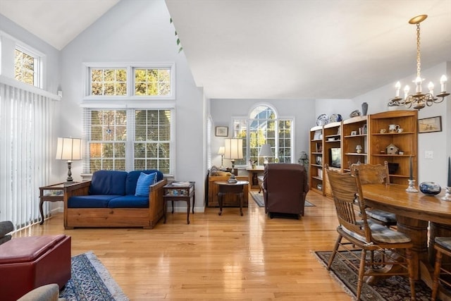 living room with high vaulted ceiling, a wealth of natural light, a chandelier, and light hardwood / wood-style flooring