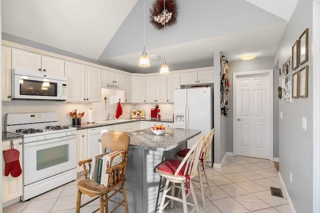 kitchen with light tile patterned flooring, white appliances, lofted ceiling, and dark stone counters