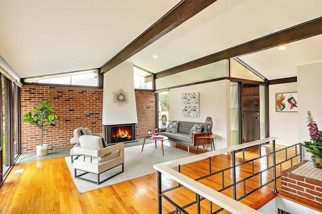 622 Pike Ave, Attleboro, MA 02703 - living area featuring lofted ceiling with beams, brick wall, hardwood / wood-style flooring, and a lit fireplace