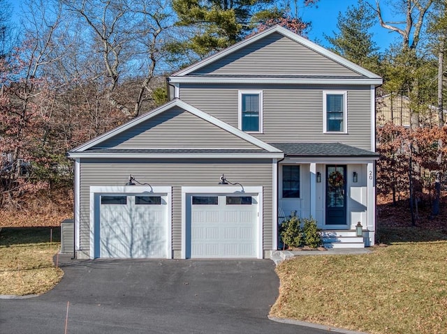 traditional home with a garage, entry steps, driveway, and a front yard