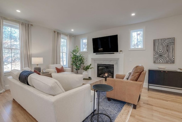 living area with a fireplace, light wood-style flooring, and recessed lighting