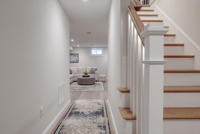 corridor featuring baseboards, visible vents, wood finished floors, stairs, and recessed lighting