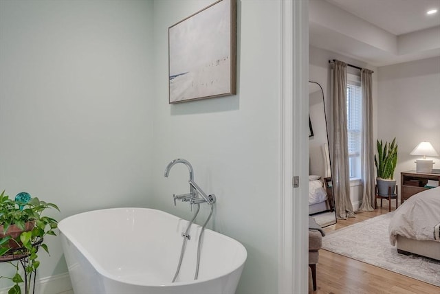 full bath with a freestanding bath, wood finished floors, connected bathroom, and baseboards