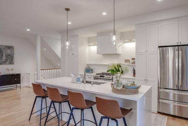 kitchen featuring freestanding refrigerator, white cabinetry, a sink, and an island with sink