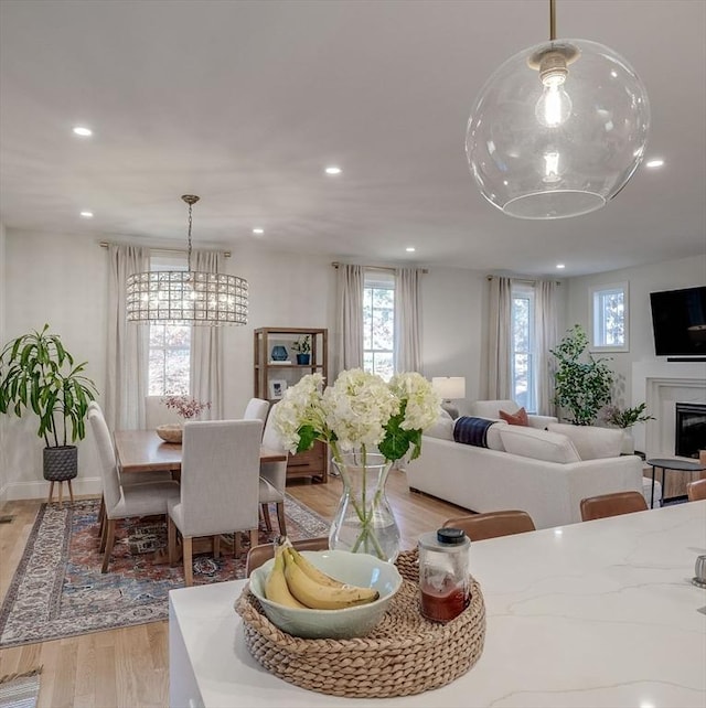 dining area featuring recessed lighting, an inviting chandelier, light wood-style floors, a glass covered fireplace, and baseboards