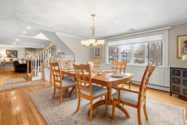 dining space featuring visible vents, ornamental molding, stairs, light wood-type flooring, and a chandelier