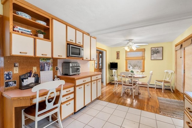 kitchen featuring light tile patterned floors, open shelves, light countertops, stainless steel microwave, and white cabinets