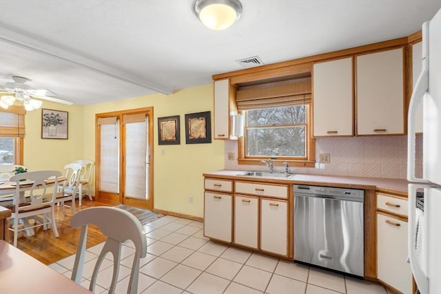 kitchen featuring a sink, light countertops, backsplash, freestanding refrigerator, and dishwasher