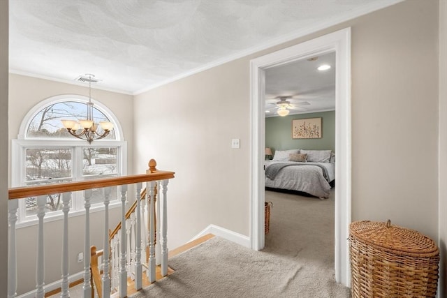 corridor with ornamental molding, carpet flooring, an upstairs landing, a chandelier, and baseboards