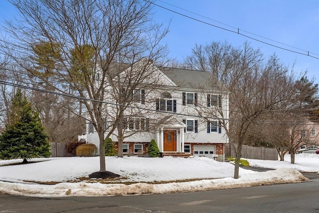 view of front facade with an attached garage, fence, and brick siding