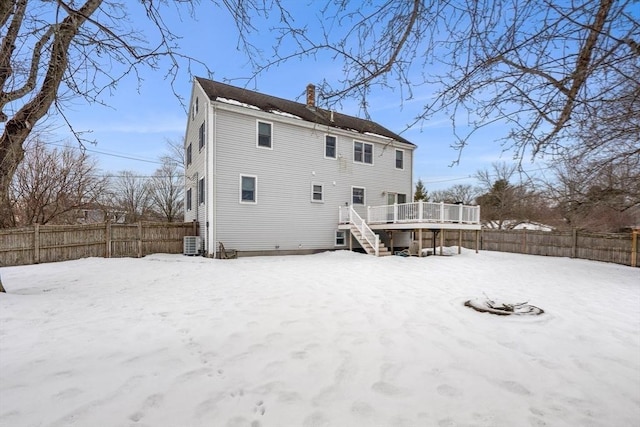 snow covered house featuring a fenced backyard, a chimney, stairs, a deck, and central AC