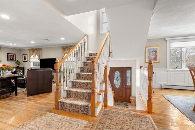 entrance foyer featuring a baseboard radiator, recessed lighting, stairway, light wood-style floors, and wainscoting