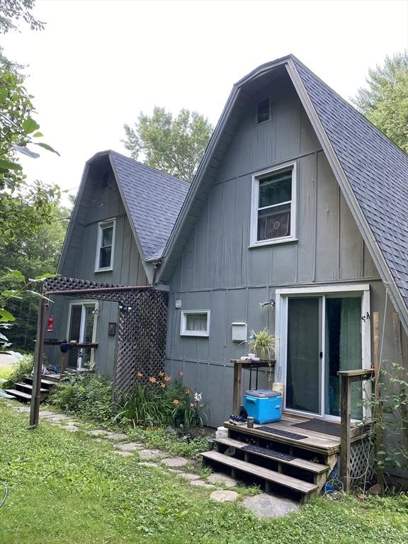 rear view of house featuring a shingled roof and a yard