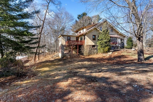 view of side of property with stucco siding, a chimney, a wooden deck, and stairs