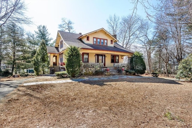 view of front of home with a porch, a chimney, and stucco siding