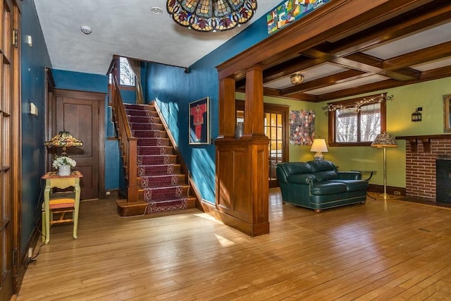 interior space with stairway, coffered ceiling, a brick fireplace, and hardwood / wood-style floors