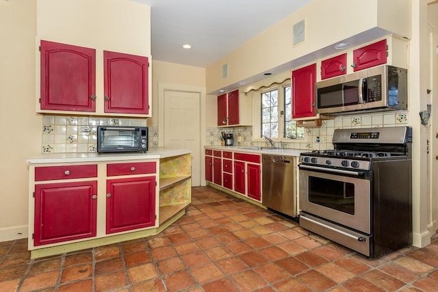 kitchen with backsplash, stainless steel appliances, light countertops, and a sink