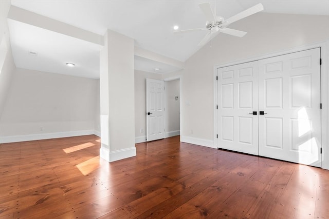 unfurnished bedroom featuring baseboards, lofted ceiling, hardwood / wood-style flooring, a closet, and a ceiling fan