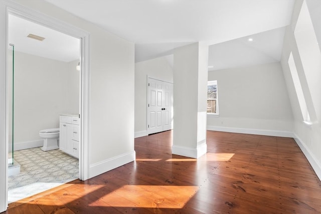 interior space featuring visible vents, wood finished floors, baseboards, and vaulted ceiling