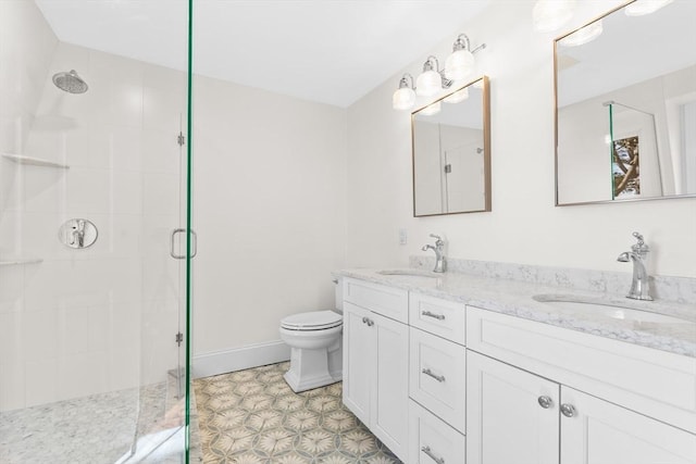 bathroom with double vanity, toilet, tiled shower, and a sink