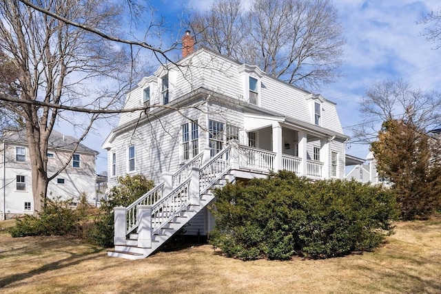 view of home's exterior featuring stairway, a lawn, and a chimney