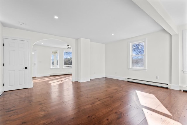 unfurnished living room with recessed lighting, arched walkways, baseboard heating, and hardwood / wood-style flooring