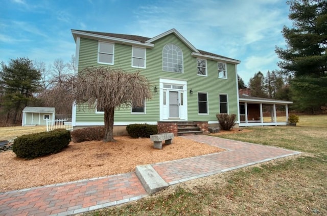 view of front of home with a storage shed and a front lawn