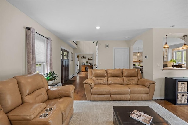 living area featuring wood finished floors, recessed lighting, arched walkways, and baseboards