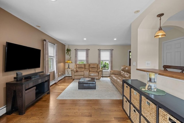 living area featuring arched walkways, wood finished floors, recessed lighting, and a baseboard radiator