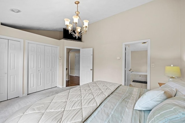 bedroom featuring a chandelier, two closets, light colored carpet, and ensuite bath