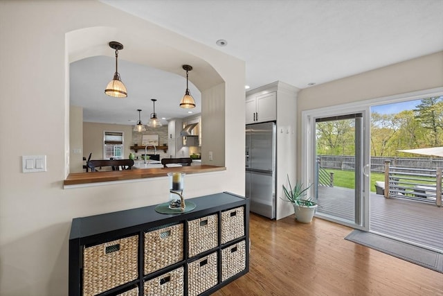 kitchen with high end fridge, plenty of natural light, wood finished floors, decorative light fixtures, and recessed lighting