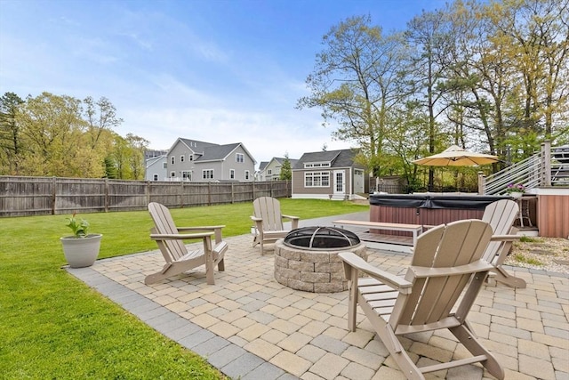 view of patio / terrace with a hot tub, an outdoor fire pit, and an outdoor structure