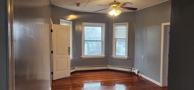 empty room featuring baseboard heating, dark wood finished floors, baseboards, and ceiling fan