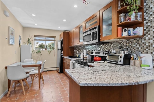 kitchen featuring stainless steel appliances, brown cabinets, backsplash, a sink, and a baseboard heating unit
