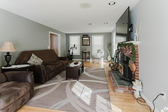 living area with a fireplace, light wood-style flooring, and baseboards