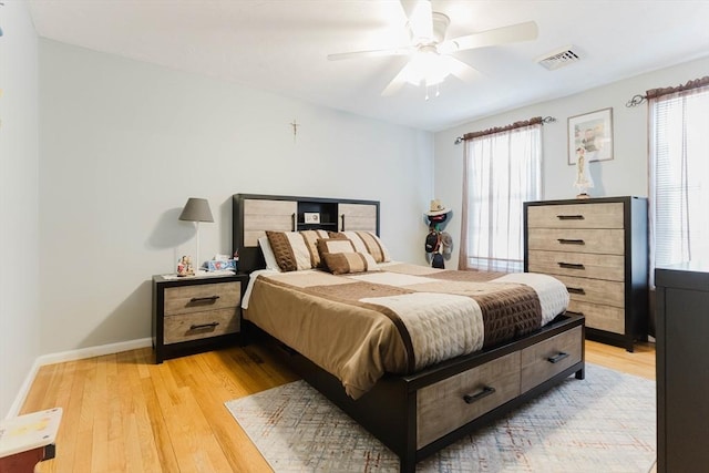 bedroom with ceiling fan, light wood finished floors, visible vents, and baseboards