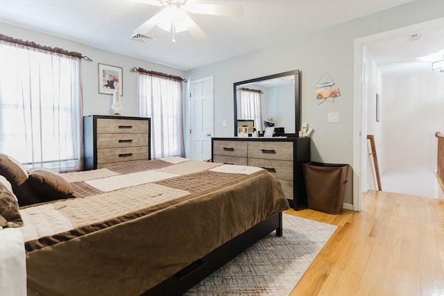 bedroom with light wood-style flooring, visible vents, and ceiling fan