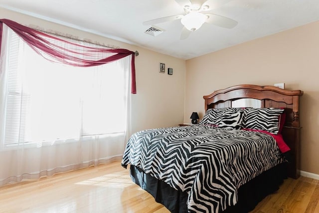 bedroom featuring a ceiling fan, baseboards, visible vents, and wood finished floors