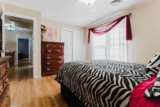 bedroom featuring light wood finished floors, a closet, visible vents, a ceiling fan, and baseboards