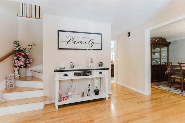 corridor with stairway, light wood-type flooring, and baseboards