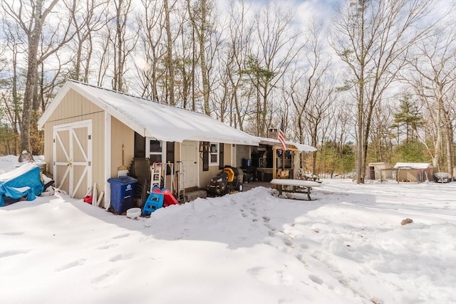 snow covered structure with an outbuilding