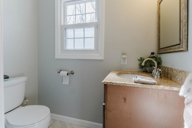 half bath with toilet, baseboards, and vanity