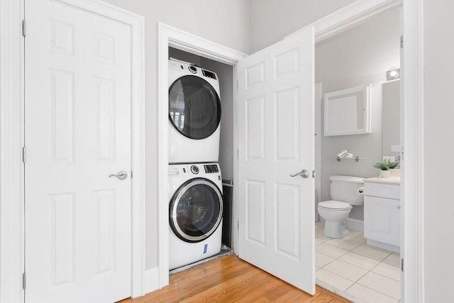 laundry room with stacked washer / drying machine and light tile patterned flooring