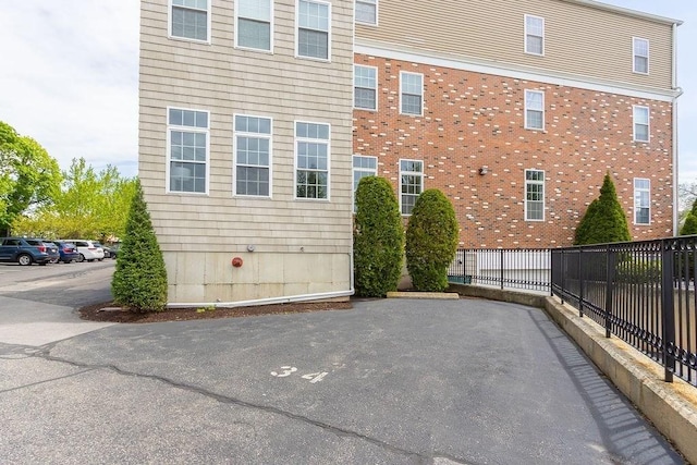 view of side of property featuring fence and brick siding