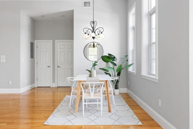 dining room featuring light wood-type flooring, a chandelier, and baseboards