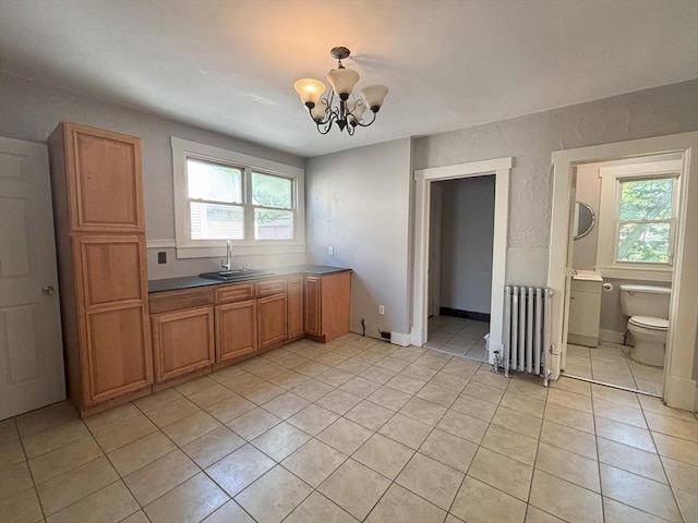 723 White St, Springfield, MA 01108 - kitchen with radiator, a sink, light tile patterned floors, a chandelier, and brown cabinetry