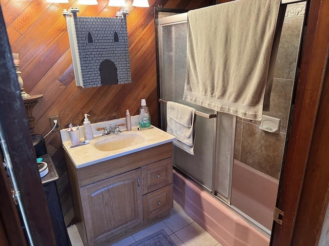 bathroom featuring vanity, tile patterned flooring, wooden walls, and bath / shower combo with glass door